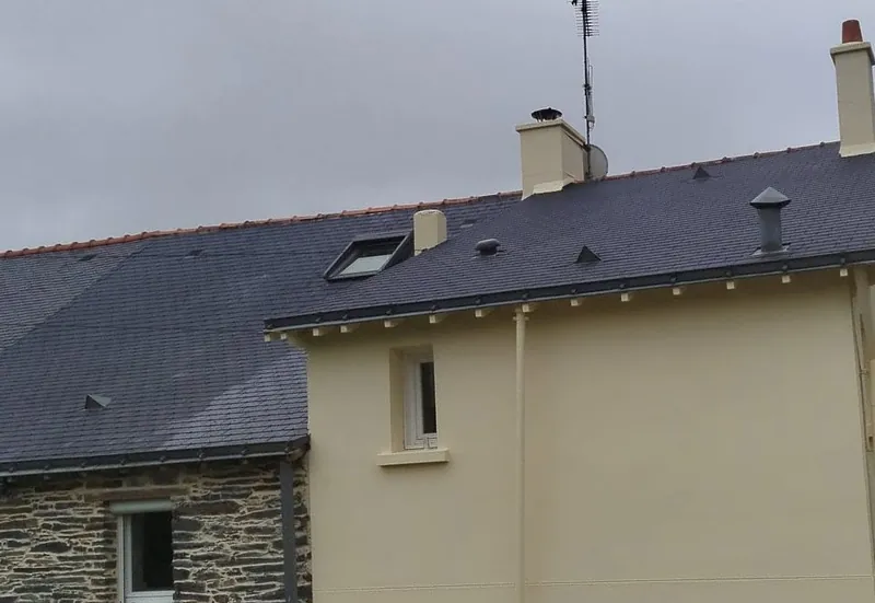 Toiture en ardoise avec velux sur une maison enduite